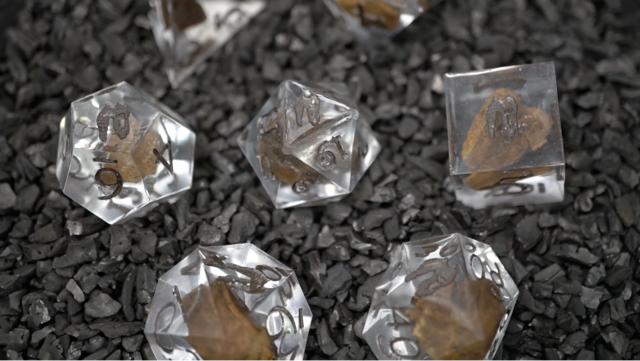 T-Rex fossil inclusion dice set with fragments suspended in clear resin